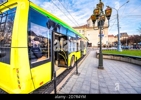 Lviv, Ukraine - January 21, 2020: Ukrainian Lvov city old town with yellow public transportation bus stop with people man sitting inside looking throu Stock Photo