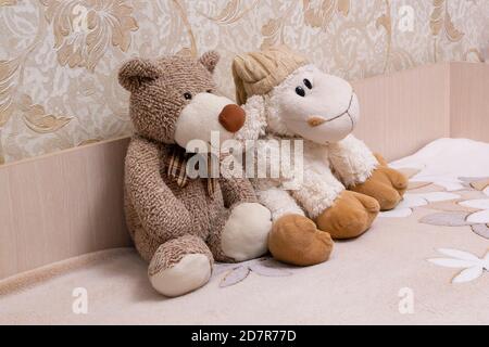 on a child's bed .sitting two soft toys-a sheep and a bear Stock Photo
