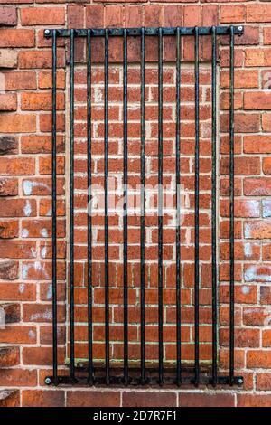 Black metal bars blocking a bricked up window in a brick wall Stock Photo