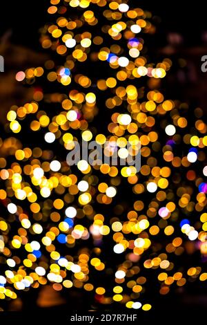 Blue, yellow and orange bokeh circles from New Year Christmas tree lights illuminations with defocused blurred view at night in Warsaw, Poland Stock Photo