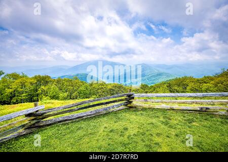 Devil's Knob Overlook with fence and green grass field meadow at Wintergreen resort town village in Blue Ridge mountains in summer clouds mist fog Stock Photo
