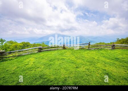 Devil's Knob Overlook with wooden fence and green grass field meadow at Wintergreen resort town village in Blue Ridge mountains in summer clouds mist Stock Photo