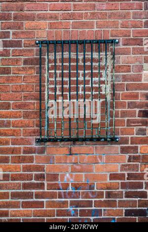 Black metal bars blocking a bricked up window in a brick wall Stock Photo
