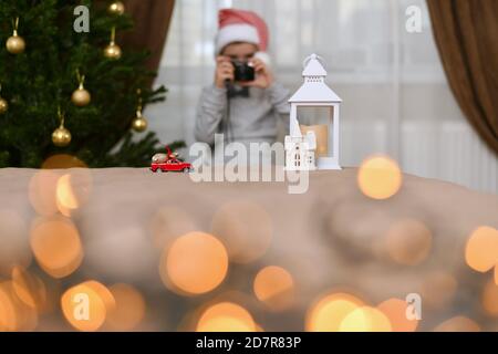 A car with a bag of gifts drives up to the house of the lantern. The child in the cap of the dwarf at takes pictures. Stock Photo