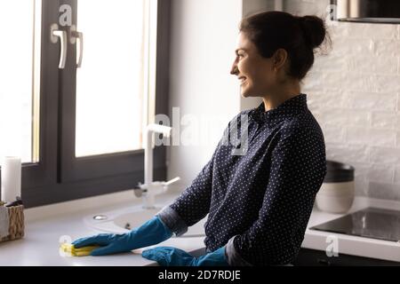 Happy Indian housewife cleaning kitchen surfaces with napkin Stock Photo