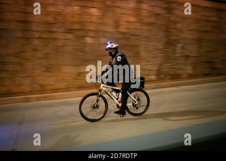 Washington, USA. 24th Oct, 2020. A police officer on a bicycle speeds by a protest march organized by the They/Them Collective in the memory of Dominique Mulkey, who was killed by police in Tampa, FL, earlier this week, in Washington, DC, on October 24, 2020 amid the coronavirus pandemic. Nearly 22 weeks after the police killing of George Floyd, near-daily protests demanding police reform and an end to systemic racism continued in Washington days after Mayor Muriel Bowser formally requested an increase in police funding.(Graeme Sloan/Sipa USA) Credit: Sipa USA/Alamy Live News Stock Photo