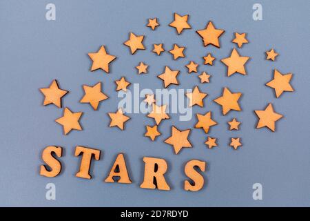 Word stars written in wooden alphabet letters over gray background. Decorating with wooden stars. Text on the table for design or concept. Stock Photo