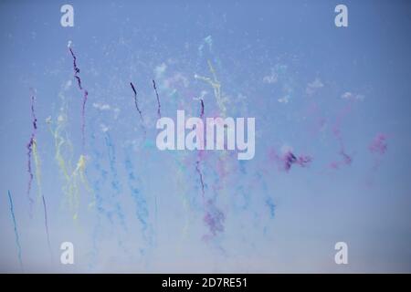 Multi-colored smoke stripes of fireworks against the blue sky. Stock Photo