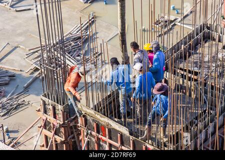 Worker pouring cement pouring into foundations and pillars formwork at building area in construction site. Stock Photo