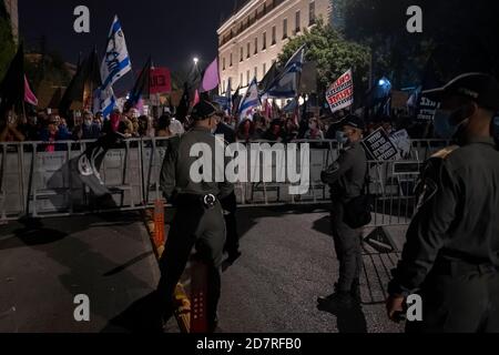 JERUSALEM, ISRAEL - OCTOBER 24: Police watch over as protesters hold placards and Israeli flags during a mass demonstration in front of prime minister's official residence on October 24, 2020 in Jerusalem, Israel. Protest organizers said in a statement that 170,000 people showed up to demonstrate against Prime Minister Benjamin across the country demanding his resignation due to his indictment on graft charges and handling of the COVID-19 pandemic. Stock Photo