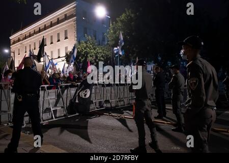 JERUSALEM, ISRAEL - OCTOBER 24: Police watch over as protesters hold placards and Israeli flags during a mass demonstration in front of prime minister's official residence on October 24, 2020 in Jerusalem, Israel. Protest organizers said in a statement that 170,000 people showed up to demonstrate against Prime Minister Benjamin across the country demanding his resignation due to his indictment on graft charges and handling of the COVID-19 pandemic. Stock Photo