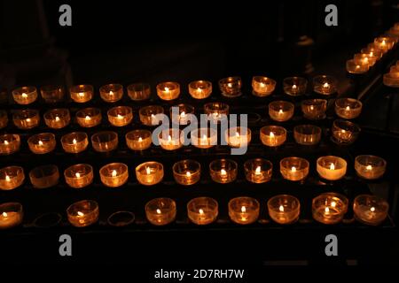 Lit tea candles and candles with copy space on black background