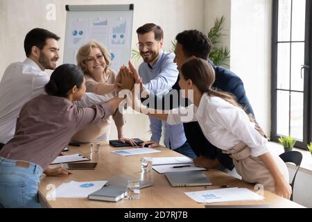 Excited diverse employees give high five at meeting Stock Photo
