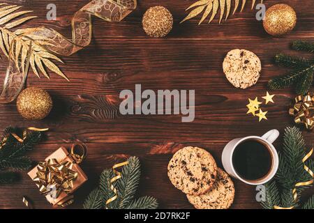 Christmas flat lay frame with coffee cup, homemade cookies, gift box, fir branches and golden decorations on dark background. Stock Photo