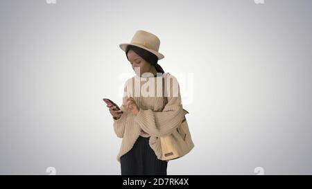 Stylish african american woman in knitwear and hat using her pho Stock Photo