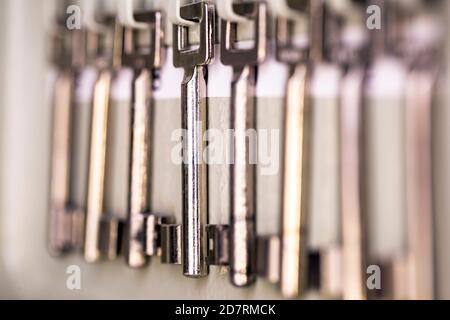 Row of old metal silver skeleton keys hanging in rack with numbers of the room. antique vintage keys Stock Photo
