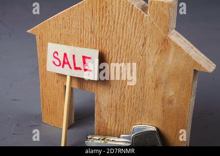 Wooden model of a house with a sale sign and keys. Close-up. Stock Photo