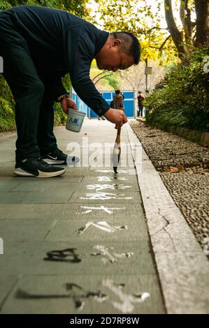 A man writes calligraphy using a water brush in Shanghai’s People’s Square. Stock Photo
