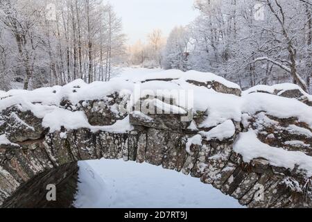 Old arch bridge over the river in the wintery landscape Stock Photo