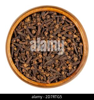Cloves in a wooden bowl. Dried aromatic flower buds of the tree Syzygium aromaticum, used as spice, in cigarettes and to create a pomander. Stock Photo