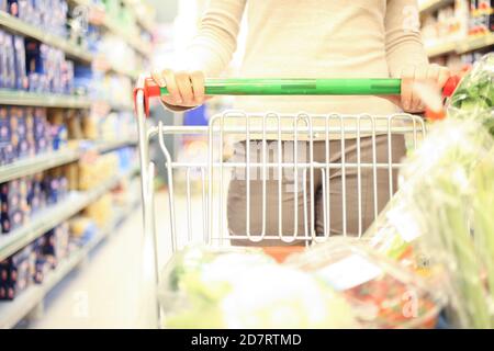 Woman pushing a cart while shopping in a supermarket Stock Photo