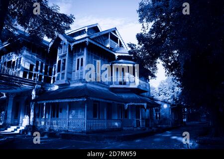 Haunted House with Dark Horror Atmosphere. Scary colonial cottage in mysterious forestland. Photo toned in blue color Stock Photo