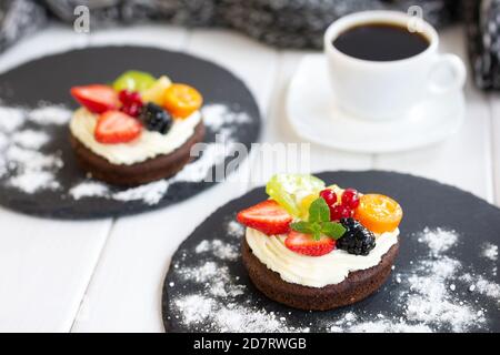 Chocolate cupcakes with cream cheese, fruits and berries. Mini cakes with custard cream. Coffee dessert Stock Photo