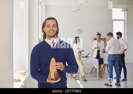 Happy company owner looking at camera holding toy rocket as symbol of new business start-up Stock Photo