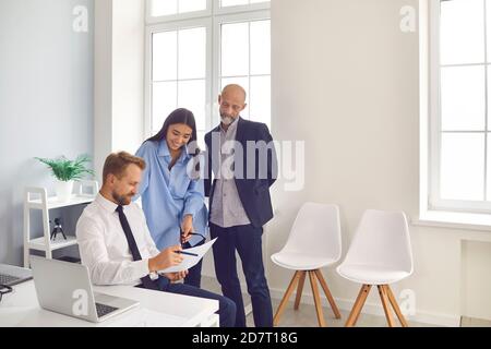 Group of various smiling corporate colleagues work together with paper documents in the office. Stock Photo