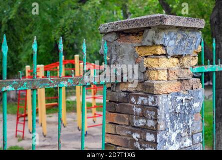 Old fence made of red brick and metal have to be repaired Stock Photo