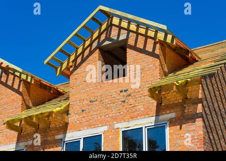 Unfinished house of brick, still under construction before installing the roof. Stock Photo