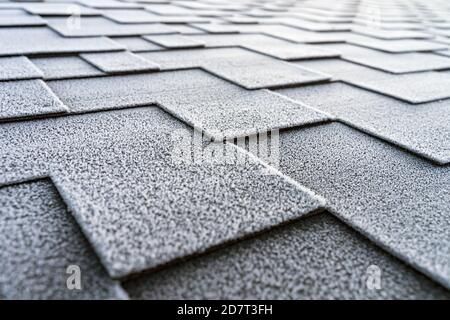 Close up view on asphalt roofing shingles covered with frost. Stock Photo