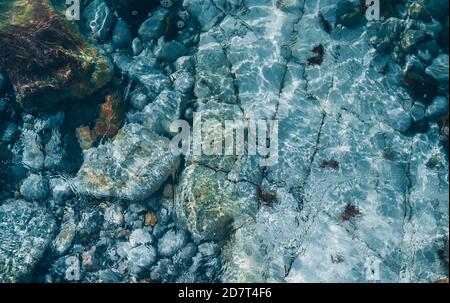 Top view of stones under transparent sea ocean blue clean water surface with refractions. Beautiful abstract natural background texture Stock Photo