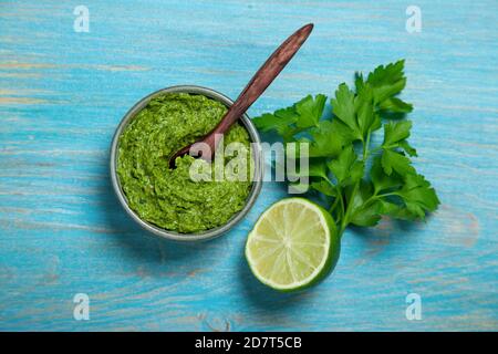 parsley chimichurri sauce (pesto) in a sauce bowl on a wooden background. view from above Stock Photo