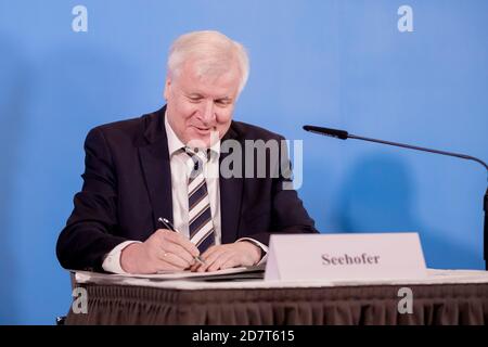 Potsdam, Germany. 25th Oct, 2020. Horst Seehofer (CSU), Federal Minister of the Interior, Building and Homeland Affairs, signs at the beginning of a press conference the agreement of the collective bargaining for the public service of the federal government and local authorities. Credit: Christoph Soeder/dpa/Alamy Live News Stock Photo