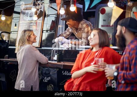 afro-american employee having conversation with a customer, smiling, with another couple standing by, talking Stock Photo