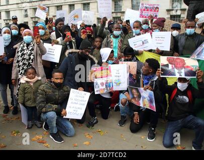 Protesters wearing facemasks hold up placards and portraits of claimed victims of the regime during the rally.Guineans in UK protest outside Downing Street after Guinea President Alpha Conde was re-elected with opposition claims that the  election was rigged. Stock Photo
