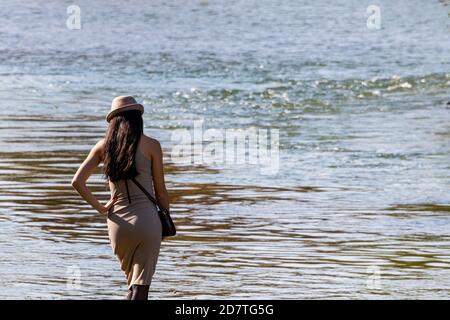 Young woman in dress, with a hut on her head watching at the water Stock Photo