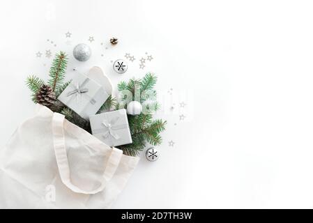 Christmas composition. Eco bag with Christmas decor, gift boxes, pine branches on white background. Christmas coming and gift delivery concept. Top vi Stock Photo
