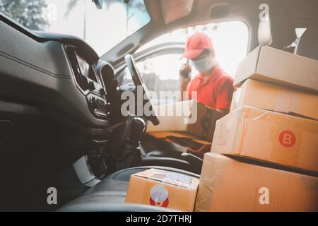 Delivery man call to customers services and wearing medical mask for safety protection from virus infection sender working with postal boxes on Stock Photo