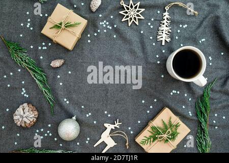 Christmas decorations with evergreen branches, snowflakes, coffee cup and gifts on gray plaid. Flat lay, top view. Christmas frame. Stock Photo