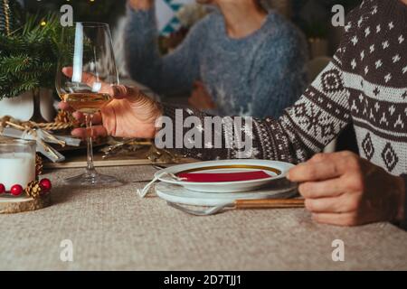 family chatting at christmas dinner, two sisters sitting at the decorated table with glasses of white wine in hand. Family Together Christmas Celebrat Stock Photo