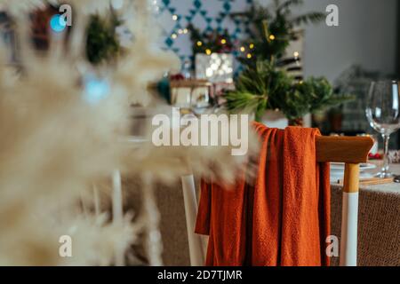wool sweater on the chair at the decorated christmas table set next to the christmas tree, concept of serenity, christmas and family holidays at home Stock Photo