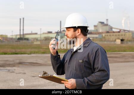 Portrait of industrial engineer standing on construction site and holding papers. Stock Photo