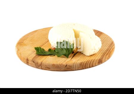 Round soft cheese and parsley on a wooden cutting board. Cheese on a cutting board isolated on a white background. Close up. Stock Photo