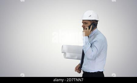 Engineer talking on phone with paperwork on gradient background. Stock Photo