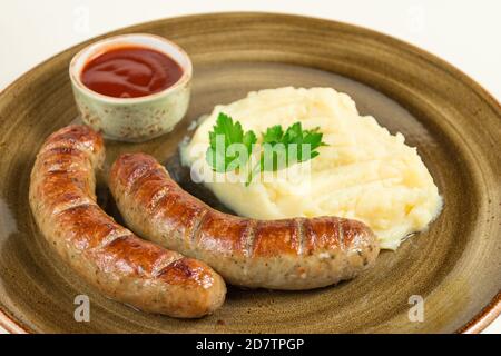 Mashed potatoes and two fried sausages with ketchup sauce in a large plate Stock Photo
