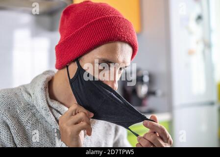 Young man is taking off his black protective mask. Concept of lifestyle and working in a pandemic. Stock Photo