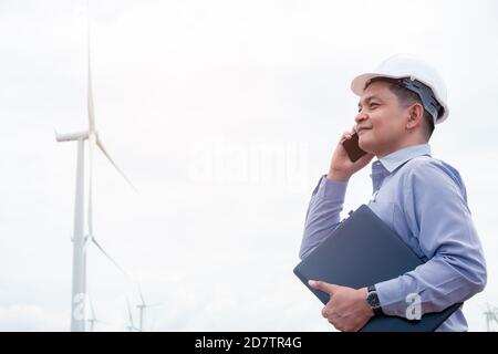 Engineers windmills are working on smartphone with the wind turbine in background Stock Photo