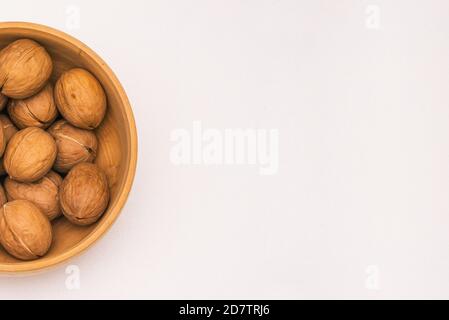 Walnuts in a wooden plate on a white background with a copy of the space. Top view, flat layout Stock Photo